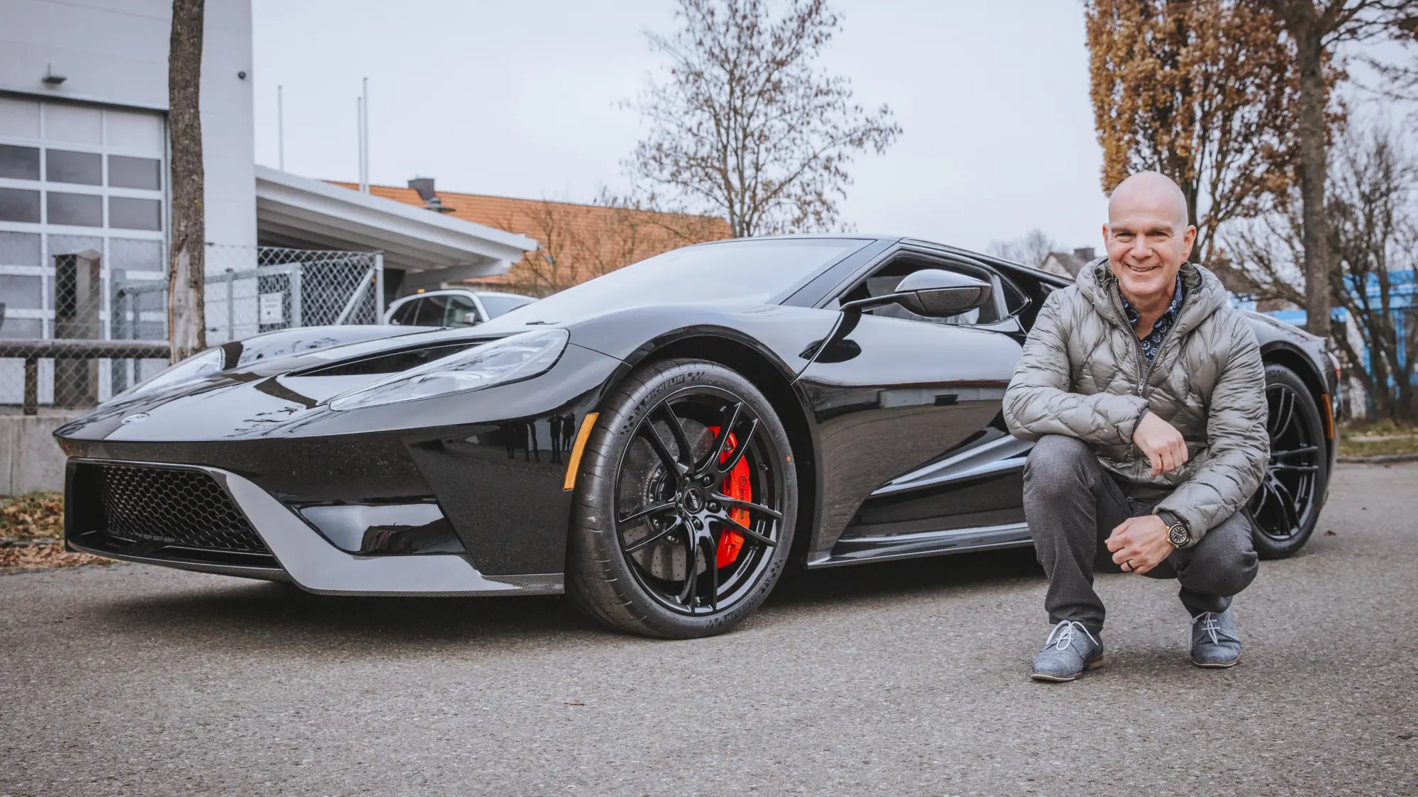 Ein Mann kniet neben einem schwarzen Ford GT vor der CULT Werkstatt