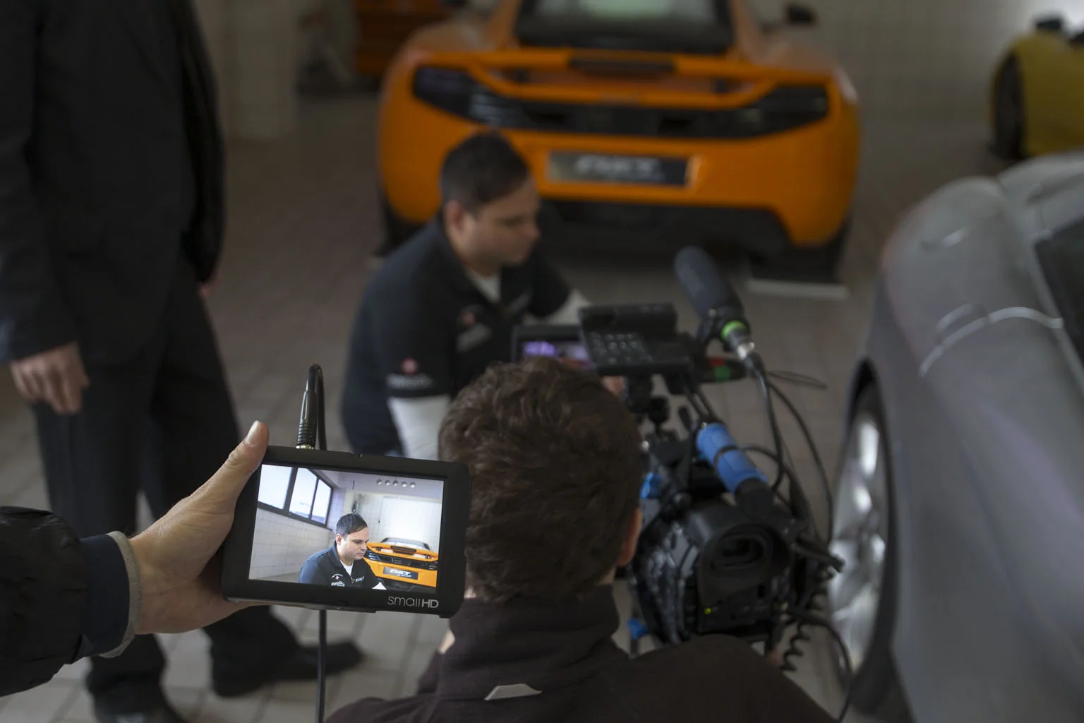 Kameramonitor zeigt einen CULT Spezialisten neben einem orangefarbenen McLaren während der Galileo-Aufnahmen
